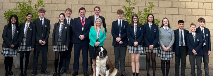 Students from Isca outside the school in front of the Isca School logo with Headteacher and Steve Race MP